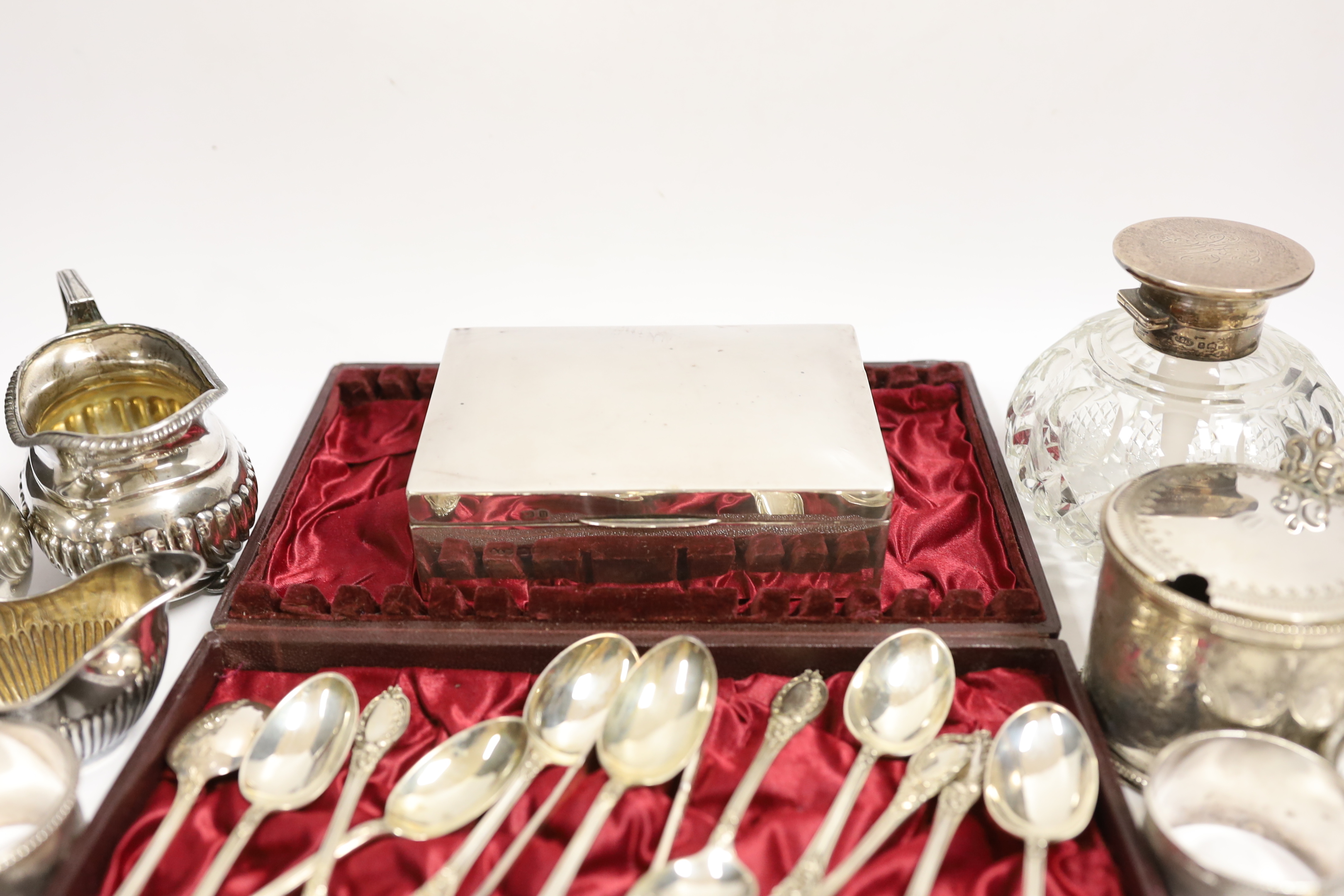 A Victorian silver mustard pot (no liner), a cased set of twelve silver teaspoons and tongs, two silver cream jugs, mounted glass scent bottle, napkin rings etc.